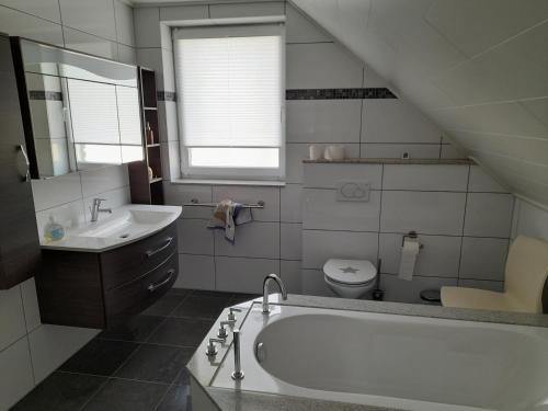 a bathroom with a tub and a sink and a toilet at Ferienhaus Deußen in Erftstadt