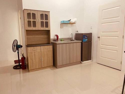 - une cuisine avec des placards en bois et un réfrigérateur dans l'établissement Deluxe studio unit at Modena Town Sq, à Tunghaan