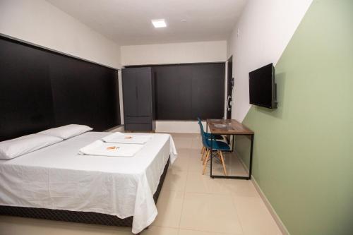 een slaapkamer met een bed, een bureau en een televisie bij Jahu Center Plaza Flats in Jaú