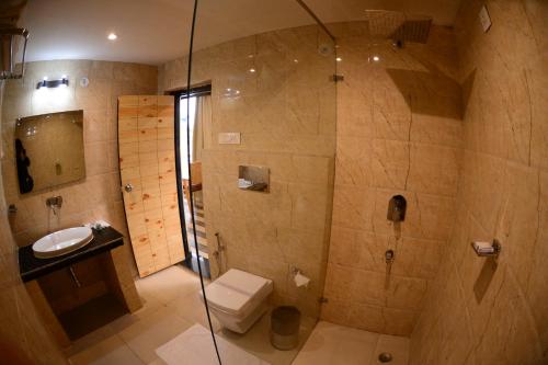 a bathroom with a shower and a toilet and a sink at The Tattwaa Corbett Spa & Retreat in Rāmnagar