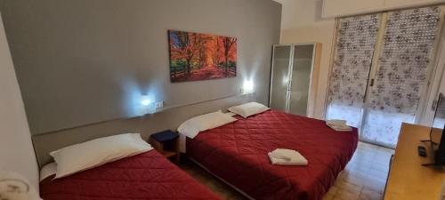 um quarto com duas camas com lençóis vermelhos e um quadro em Hotel Indicatore Budget & Business At A Glance em Campi Bisenzio