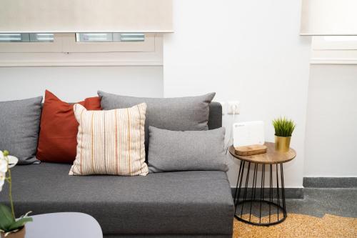 a living room with a gray couch with pillows at HomeResidence 2 in Ermoupoli