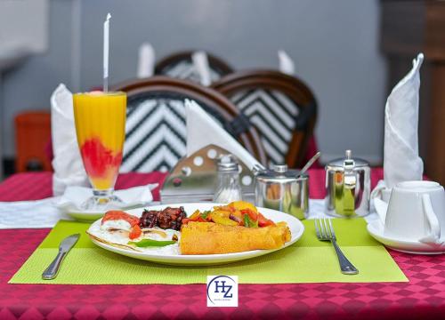 a table with a plate of food and a drink at Hotel Zesper in Kisii