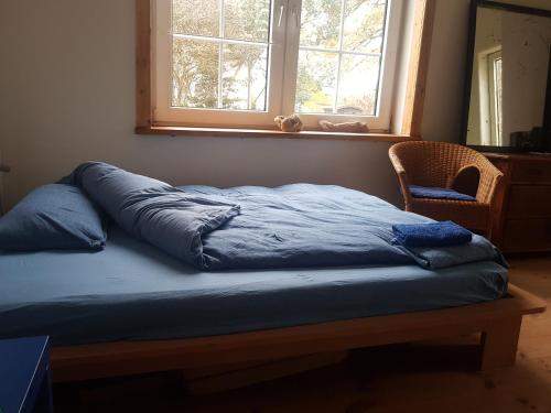 a bed with a blue comforter sitting under a window at Gästezimmer Neritz 10 