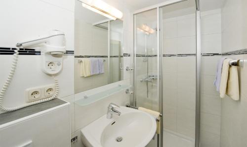 a white bathroom with a shower and a sink at Pension Riedlsperger in Saalbach Hinterglemm