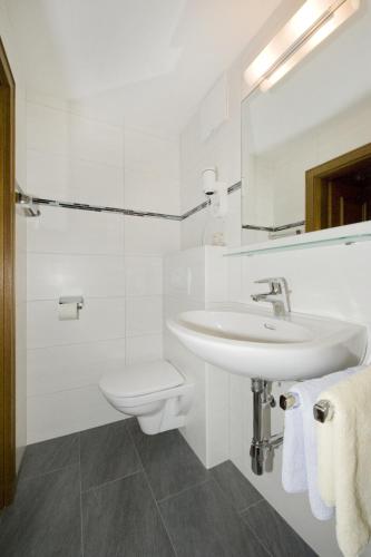 a white bathroom with a sink and a toilet at Pension Riedlsperger in Saalbach Hinterglemm