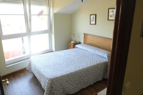 1 dormitorio con 1 cama y 2 ventanas en Apartamento Playa de La Atalaya, en Ribadesella