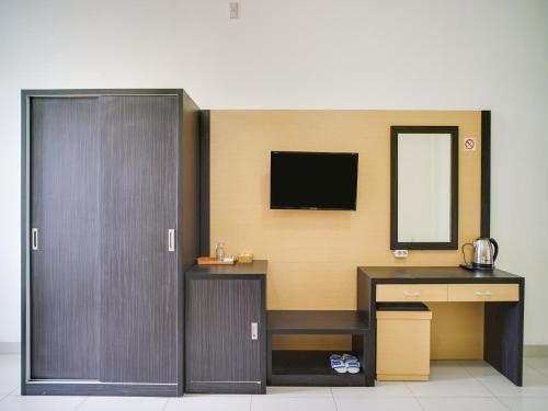 a room with a desk and a tv on the wall at SUPER OYO Capital O 540 Esther Hotel in Balige