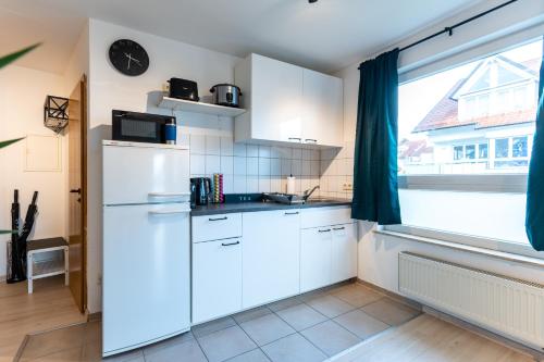 a kitchen with white cabinets and a large window at Mercedes I Stuttgart I Kitchen I Home Office I Parkplatz in Böblingen