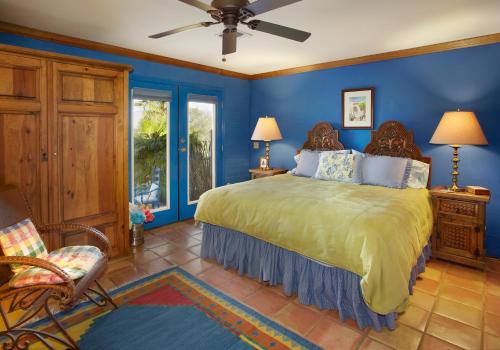 1 dormitorio con 1 cama con paredes azules y ventilador en Cactus Cove Bed and Breakfast Inn, en Tucson