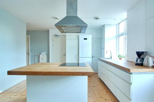 una cucina con mobili bianchi e un piano di lavoro in legno di Large Modern Apartments By Meat Packing District in central Copenhagen a Copenaghen