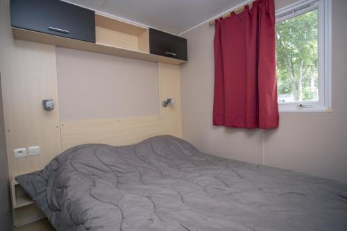 a bed in a bedroom with a red curtain at Camping du Lac in Foix
