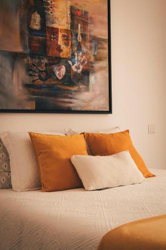 a bed with orange pillows and a painting above it at Casa da Bia in Conceição
