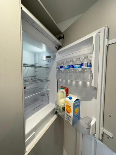 an open refrigerator filled with bottles of water and milk at Aspen Villa in Hemel Hempstead