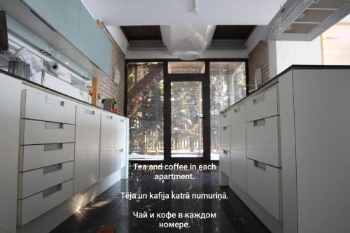 a kitchen with white cabinets and a large window at Champêtre Park View Apartments in Rīga