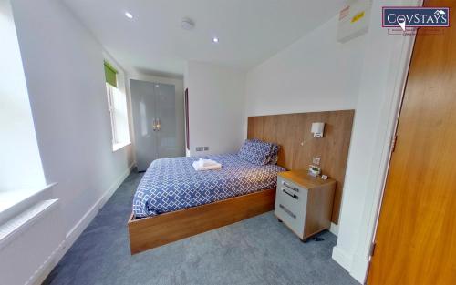 a small bedroom with a bed and a night stand at Victoria House - Deluxe Studios in Coventry City Centre, free parking, by COVSTAYS in Coventry