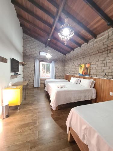 a room with two beds and a table and a tv at Bosque São Francisco in Chapada dos Guimarães