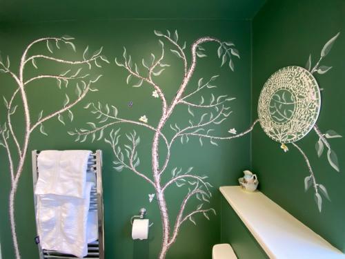 a bathroom with a green wall with a tree mural at Artist's eclectic Town House close to river in Woodbridge
