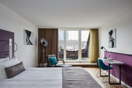 a hotel room with a bed and a desk and a window at Hotel Indigo - Dusseldorf - Victoriaplatz by IHG in Düsseldorf