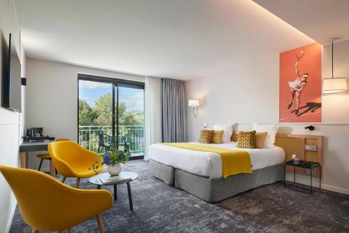 ビオットにあるMouratoglou Hotel & Resortのベッドと黄色の椅子が備わるホテルルームです。