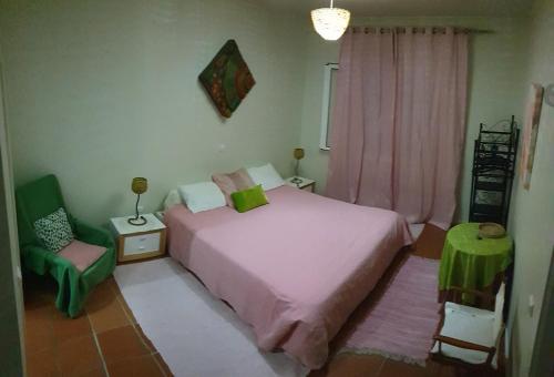 um quarto com uma cama rosa e uma cadeira em House pc em Porto da Cruz