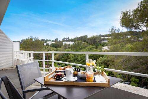 ein Tablett mit Speisen auf einem Tisch auf einem Balkon in der Unterkunft Mouratoglou Hotel & Resort in Biot