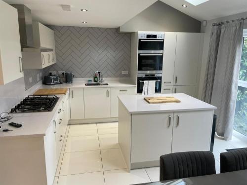 a kitchen with white cabinets and a stove top oven at The Townhouse @Thorpe Road in Peterborough