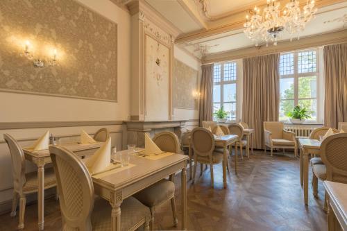 a restaurant with tables and chairs and a chandelier at Amrâth Hotel Bigarré in Maastricht