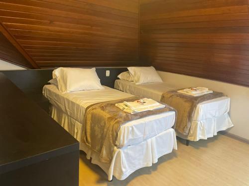 two beds in a room with two tables at Hotel Glamour da Serra in Gramado
