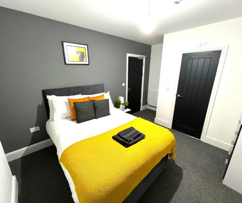 a bedroom with a large bed with a yellow blanket at Chantry Suites in Grimsby