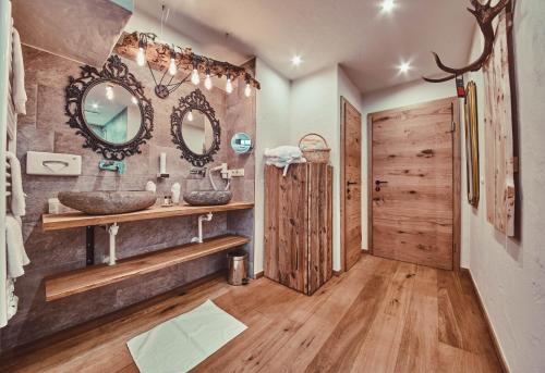 ein Bad mit einem Waschbecken und einem Spiegel in der Unterkunft Dorfhotel Glücksschmiede in Saalbach-Hinterglemm