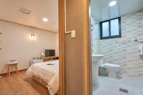 ein Schlafzimmer mit einem Bett und ein Badezimmer mit einem WC in der Unterkunft K'STAY Sinchon in Seoul