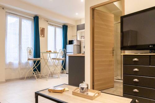 - un salon avec une télévision et une table dans l'établissement Studio Tamaris au coeur historique de Montauban, à Montauban