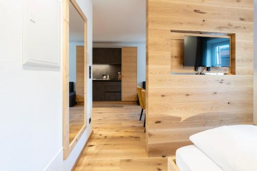 Habitación con paredes de madera y puerta corredera con TV. en Residence Kugler, en San Candido