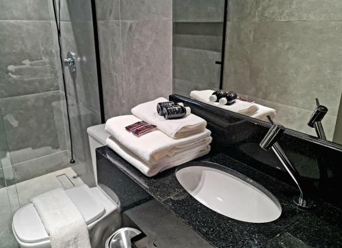 a bathroom with a sink and a toilet and towels at Seasons BC in Cabeçudas