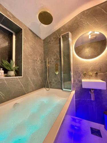 a bathroom with a tub and a sink at The Lansdowne Hideaway - Brought to you by Coastline Retreats - Newly Refurbished Town centre, Close to beach, Large Jet bath with TV, Netflix, swing and Parking Included in Bournemouth