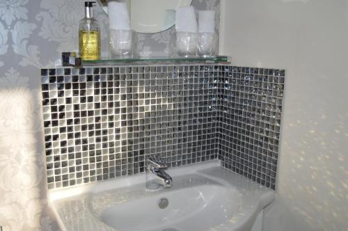 a bathroom with a sink with a tiled wall at Ellerbrook House in Windermere