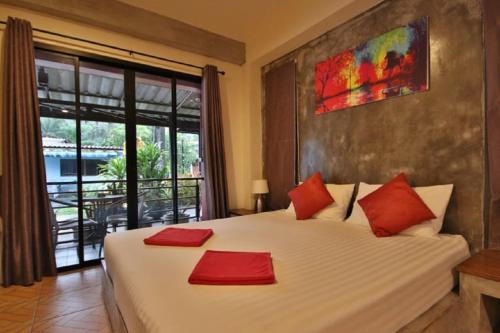 um quarto com uma grande cama branca com almofadas vermelhas em The Morning mini house aonang em Praia de Aonang