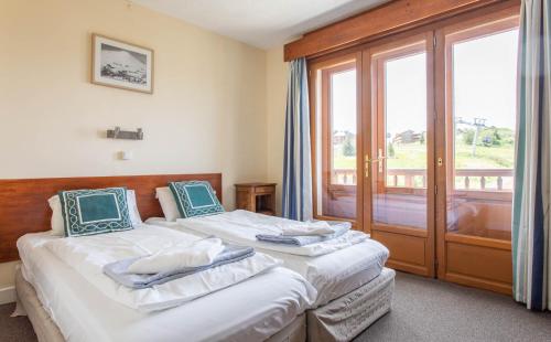 two beds in a room with a window at Hotel Le Chamois in L'Alpe-d'Huez