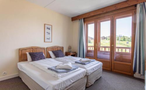 a bedroom with a bed and a sliding glass door at Hotel Le Chamois in L'Alpe-d'Huez