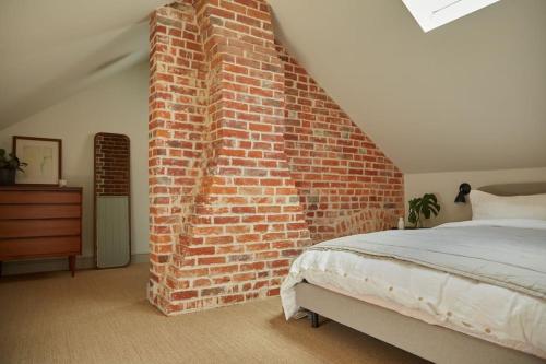 1 dormitorio con pared de ladrillo junto a la cama en Converted Chapel with Scandi design interior, en New Buckenham