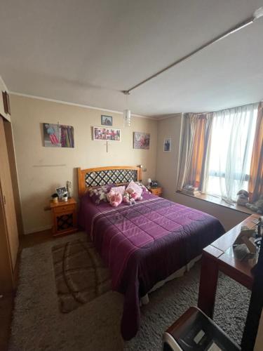 Un dormitorio con una gran cama púrpura con almohadas rosas en Departamento en Condominio Cerrado La Florida en Santiago
