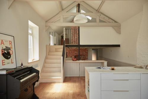 a kitchen with a piano and a staircase in a room at Converted Chapel with Scandi design interior in New Buckenham