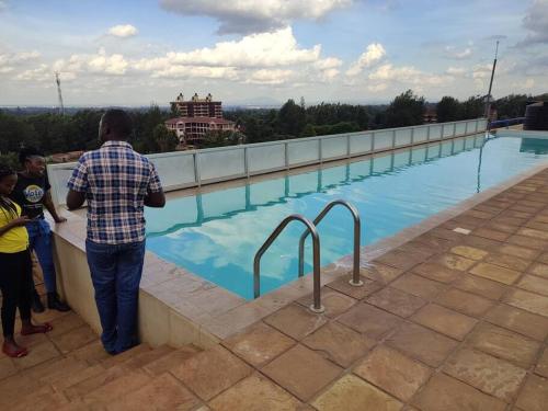 un hombre de pie junto a una pared junto a una piscina en Pretty stay en Nairobi