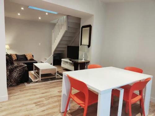 sala de estar con mesa blanca y sillas rojas en La petite maison, en Dinan