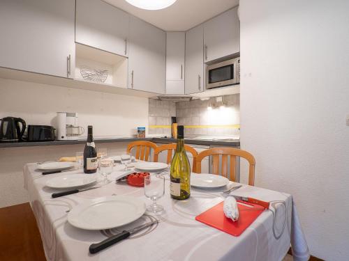 - une table avec des assiettes blanches et des bouteilles de vin dans l'établissement Apartment Balcons d'Olympie 305 - A by Interhome, aux Menuires