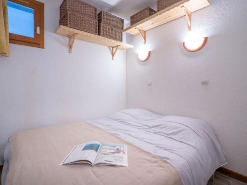 a bedroom with a bed with a book on it at Apartment Balcon d'Olympie 745 - B by Interhome in Les Menuires
