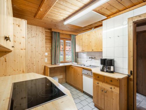 a large kitchen with wooden walls and wooden cabinets at Chalet Gnadenalm - OBR103 by Interhome in Obertauern