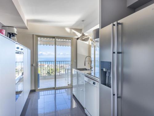 une cuisine avec des appareils blancs et une grande fenêtre dans l'établissement Apartment Les Miradors by Interhome, à Menton