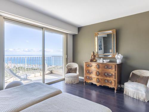 een slaapkamer met een bed en een spiegel en een balkon bij Apartment Les Miradors by Interhome in Menton
